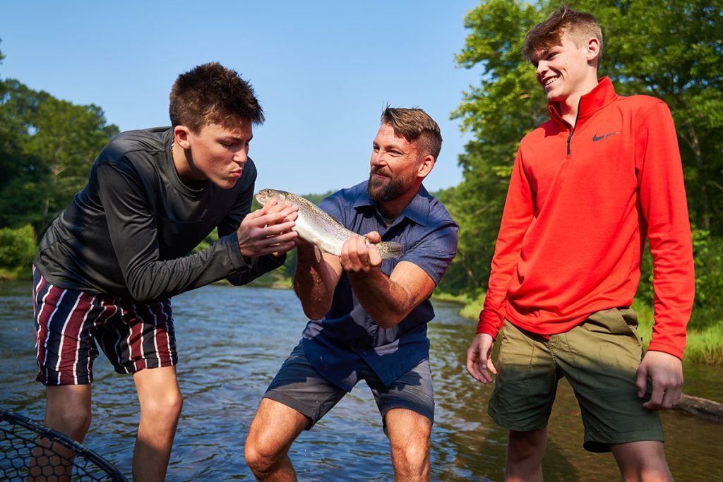 A dad and his two sons joking around on a rainbow trout fly fishing trip on the Lower Mountain Fork River in Beavers Bend State Park