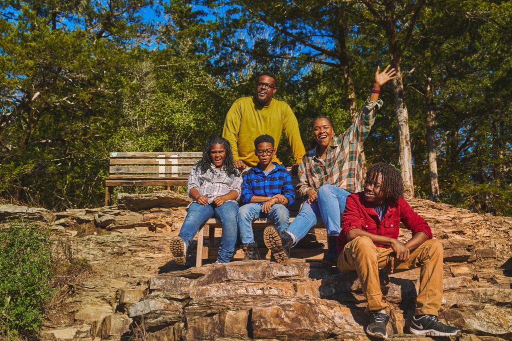 A family of five stops for a rest on the Cedar Bluff Nature Trail in Beavers Bend State Park.